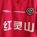 Domowa koszulka piłkarska Chengdu Blades z sezonu 2006 w kolorze czerwonym marki Umbro.