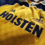 Wyjazdowa koszulka Tottenham Hotspur z sezonu 1999-00 w kolorze żółto-granatowym marki Adidas.