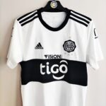 Domowa koszulka Club Olimpia z sezonu 2020 w kolorze biało-czarnym marki Adidas.