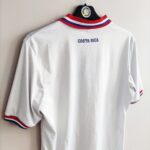 Wyjazdowa koszulka Kostaryka z roku 2015 w kolorze białym marki New Balance.