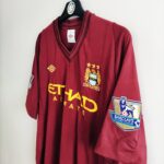 Wyjazdowa koszulka Manchester City (#8 S. Nasri) z sezonu 2012-13 w kolorze burgundowym marki Umbro.